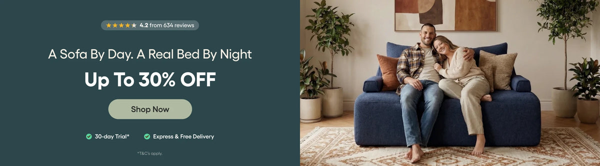Promotional banner for a sofa deal, featuring a dark teal left panel with text reading 'A Sofa By Day, A Real Bed By Night, Up To 30% OFF' and a right panel showing a couple relaxing on a blue upholstered sofa in a living room.