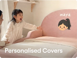 A child wearing a white long-sleeve shirt sits beside a bed with a pink personalized headboard cover featuring a cartoon girl illustration and the name 'maya'. Large text at the bottom reads 'Personalised Covers'.