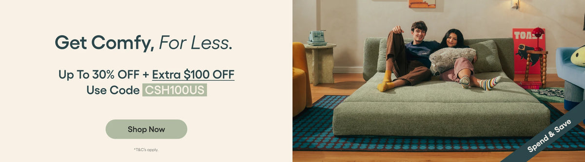 Promotional banner with text on the left reading 'Get Comfy, For Less.' and a lifestyle scene on the right showing a couple lounging on a large green sofa in a living room.